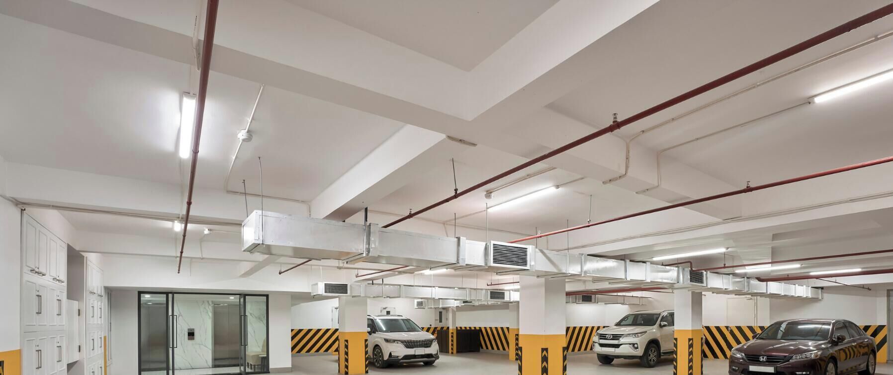 A multi-level parking garage with white walls, black and yellow safety markings, and several parked cars.