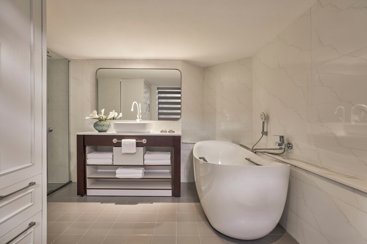 A modern bathroom with a freestanding bathtub, a vanity with a mirror, and a towel rack.