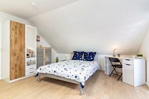 A bedroom with a bed, a desk, and a wardrobe.