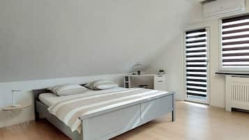 A bedroom with a bed, bedside table, lamp, and a window with blinds.