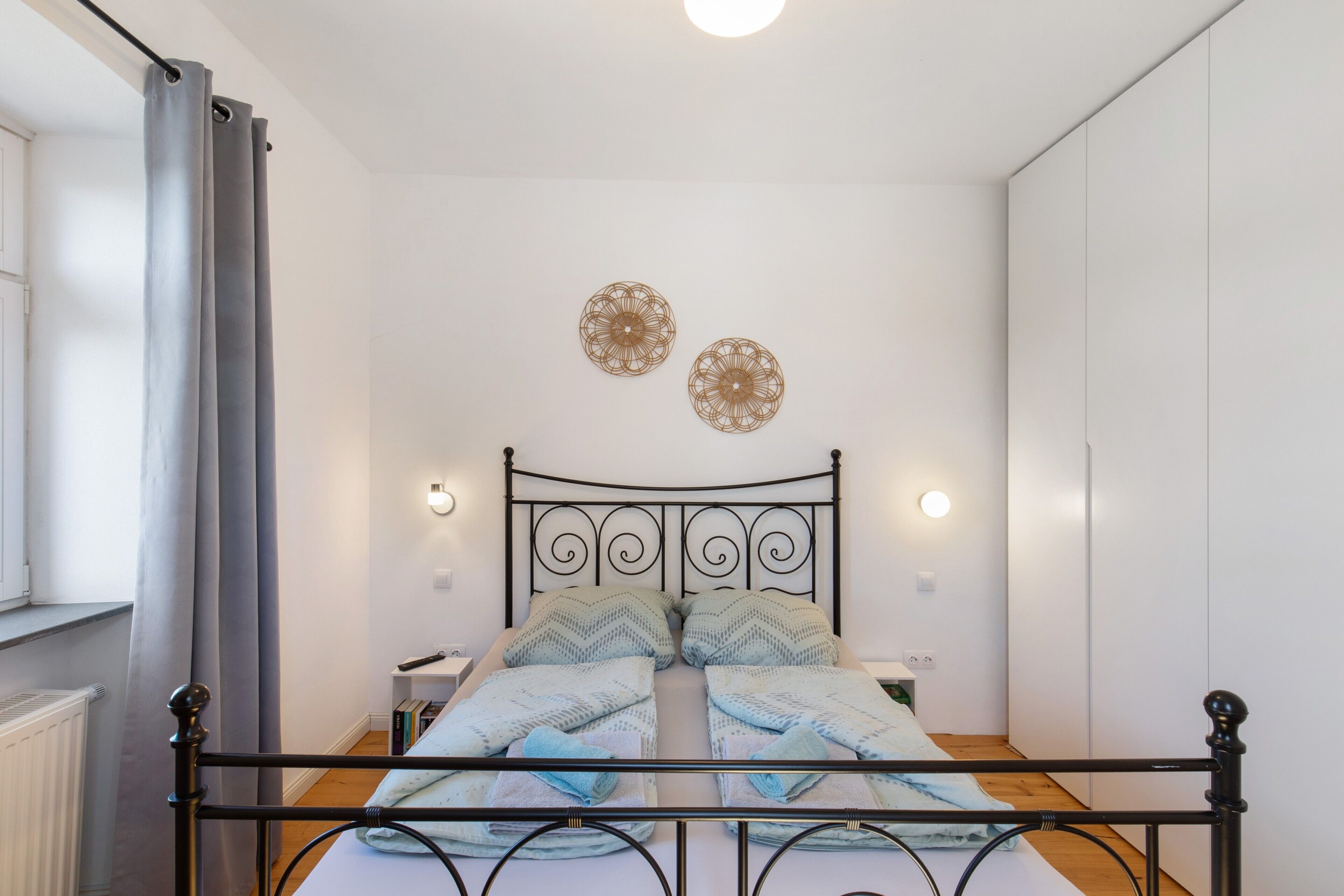 Een bed met een metalen frame, twee wandlampen en decoratieve wandkunst.
