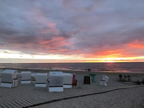 A beach with lounge chairs and a wooden walkway.