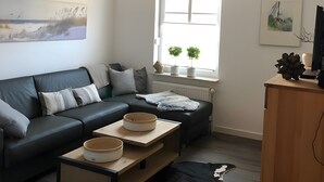 Een moderne woonkamer met een bank, salontafel en een zwarte hond.