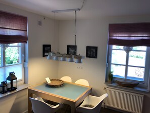 Zona pranzo con tavolo, sedie, lampadario e opere d'arte alle pareti.