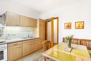 Une cuisine avec des meubles de rangement en bois, un évier et une table à manger avec des chaises.