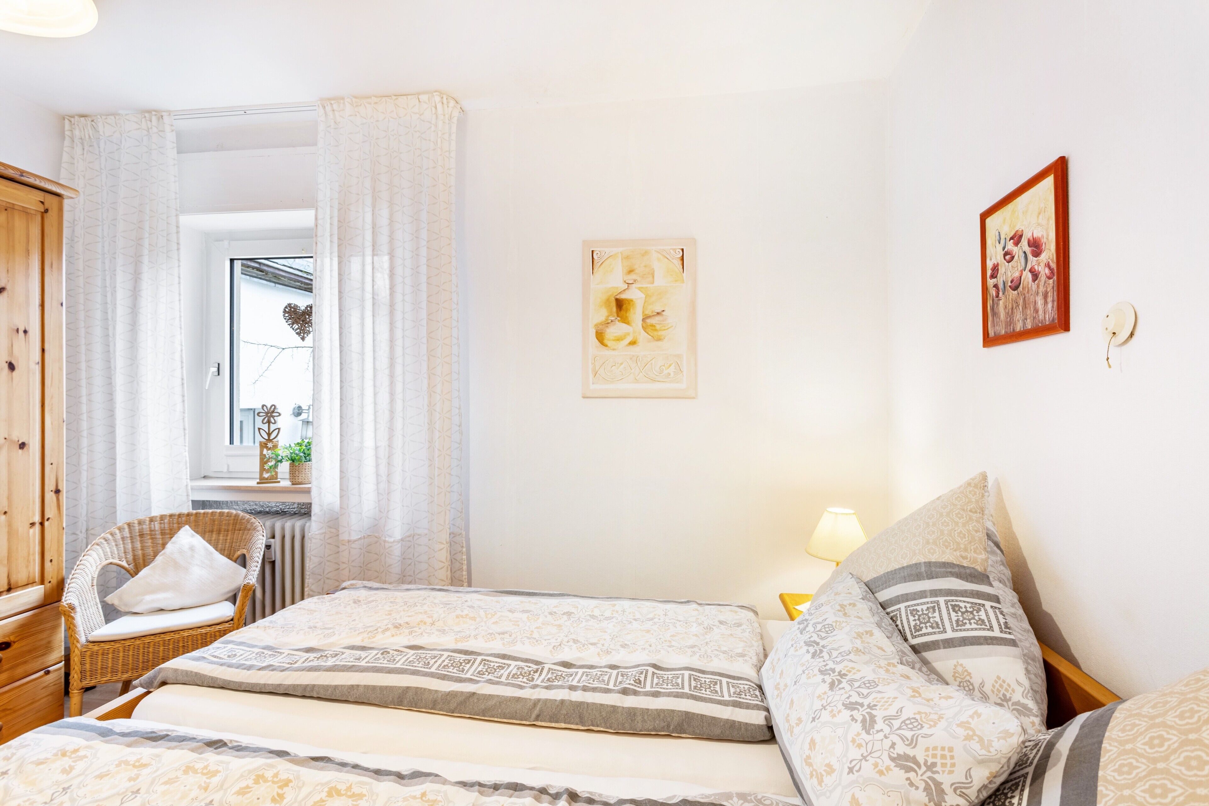 A bedroom with a bed, a chair, a window, and a wall with a picture.
