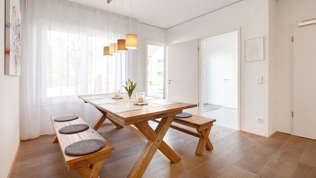 Un comedor moderno con una mesa de madera, bancos e iluminación colgante.