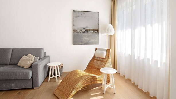 A modern living room with a grey sofa, a wicker lounge chair, a small white table, and sheer curtains. - Room '2' with Shared Terrace and Wi-Fi (Vöhringen)