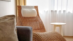A wicker lounge chair with a pillow, a small round table, and a sofa. - Room '2' with Shared Terrace and Wi-Fi (Vöhringen)