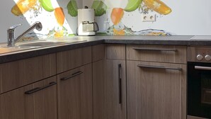 A kitchen with a coffee maker, wooden cabinets, and a sink.