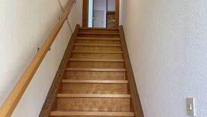 A wooden staircase with a handrail, leading to a door at the top.