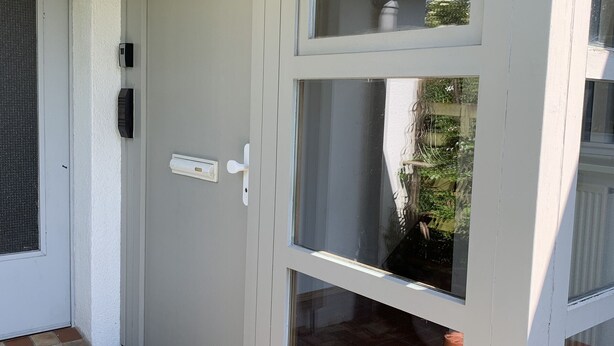 A white door with a mail slot and a window.