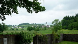 A rural landscape with a church, open fields, and a stone wall.