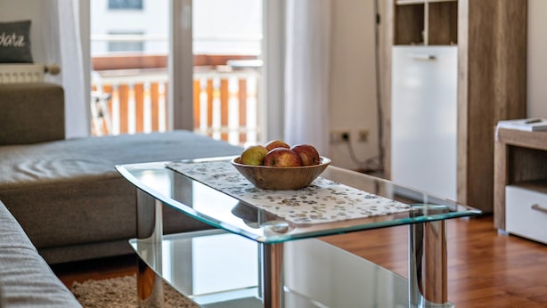 A modern living room with a glass coffee table, a sofa, and a bowl of apples on the table. - Apartment '01' with Shared Terrace, Balcony and Wi-Fi (Lindau)