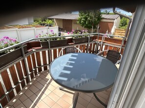 Un patio con un tavolo rotondo e sedie, circondato da una recinzione in legno e piante in vaso.