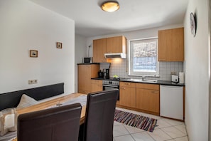 A compact kitchen with wooden cabinets, a microwave, a stove, and a dishwasher. - Apartment '01' with Shared Terrace, Balcony and Wi-Fi (Lindau)