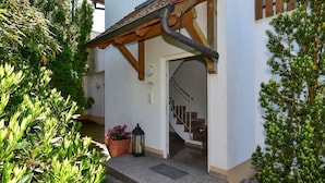 A building entrance with a wooden porch, a potted plant, and a staircase leading inside. - Apartment '01' with Shared Terrace, Balcony and Wi-Fi (Lindau)