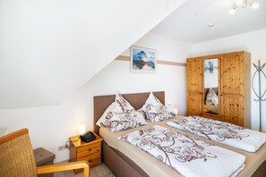 Une chambre à coucher comprenant un lit, une table de chevet, une lampe, une armoire et un tableau accroché au mur.