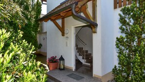 A building entrance with a wooden porch, a potted plant, and a staircase leading inside. - Apartment '02' with Shared Terrace, Balcony and Wi-Fi (Lindau)
