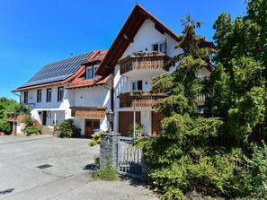 A two-story building with a sloped roof, solar panels, and a balcony with potted plants. - Apartment '02' with Shared Terrace, Balcony and Wi-Fi (Lindau)