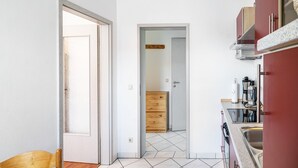 A kitchen with a tiled floor, wooden cabinets, and a visible door leading to another room. - Apartment '02' with Shared Terrace, Balcony and Wi-Fi (Lindau)