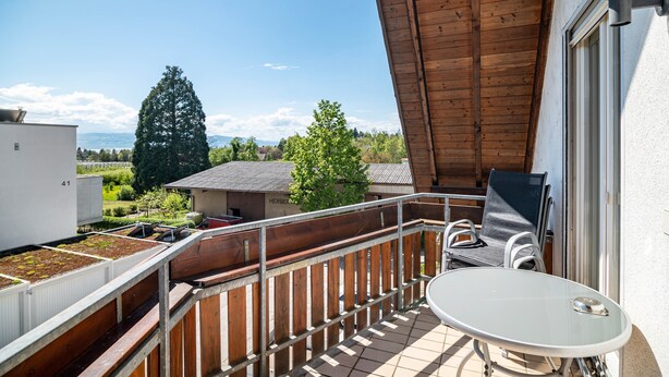 A balcony with a table and chairs, a view of greenery and a building in the background. - Apartment '02' with Shared Terrace, Balcony and Wi-Fi (Lindau)