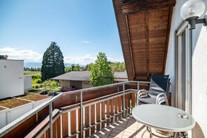 Un balcon avec une table et des chaises, une vue sur la verdure et un bâtiment en arrière-plan.