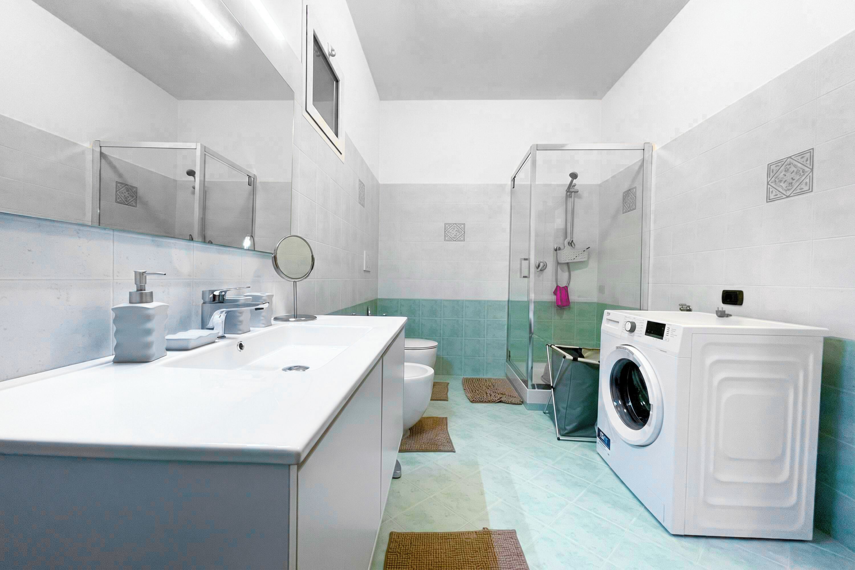 Un baño moderno con un lavamanos grande, un espejo, un inodoro, una ducha y una lavadora.