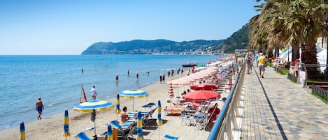 Enjoy the serene beachside promenade with stunning sea views, sun loungers, and shaded areas under umbrellas.