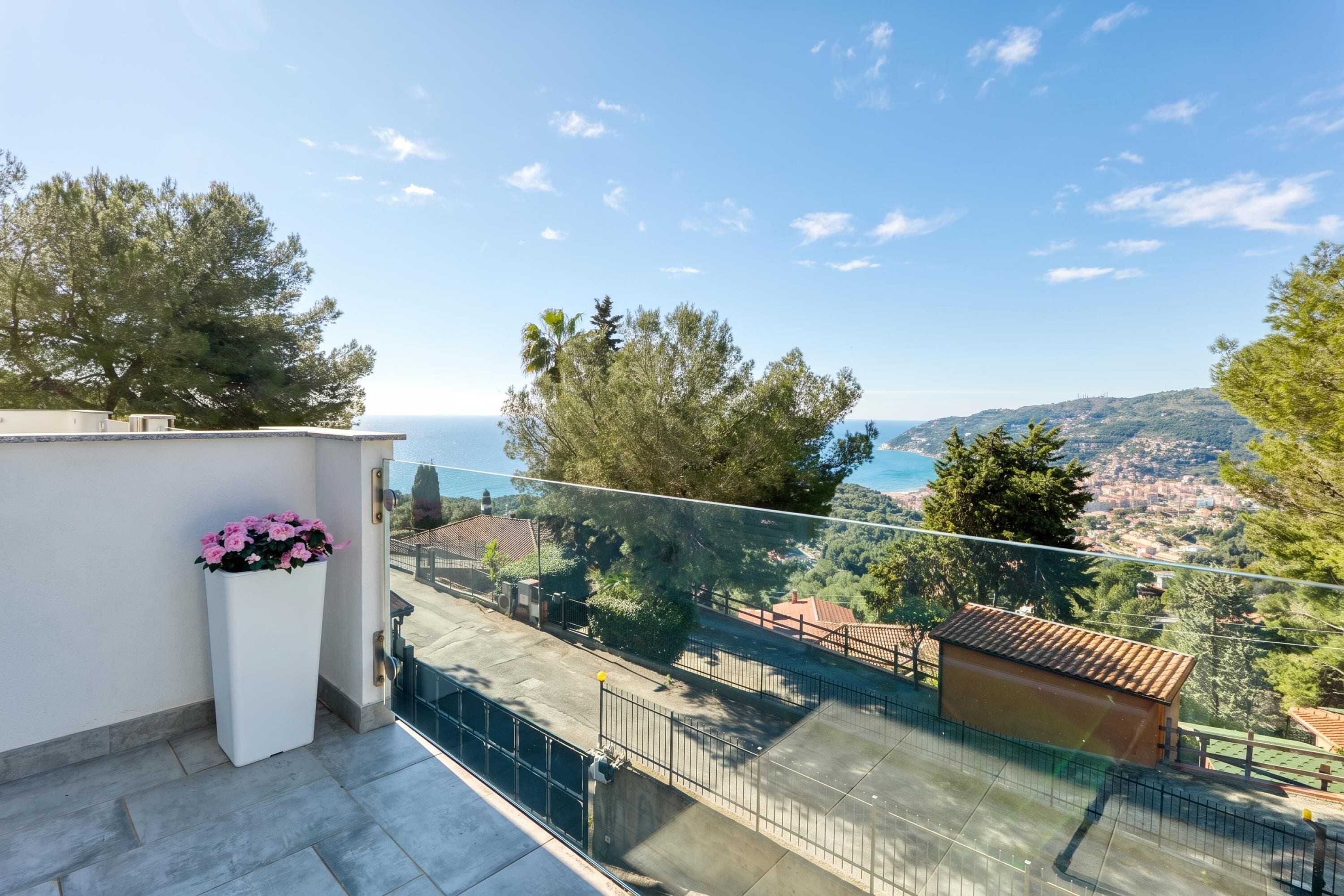 A balcony with a clear view of the sea and a distant town.
