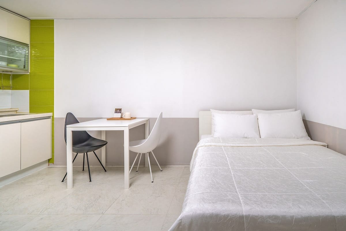 A small, clean room with a bed, a desk, and a chair.