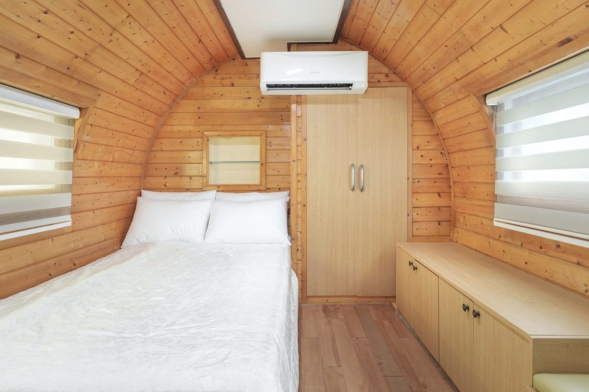 A cozy bedroom with a bed, a wardrobe, and an air conditioning unit.
