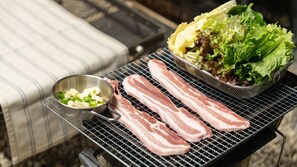 A grill with bacon strips and a bowl of sliced jalapeños. - Yangyang Lira Camp (Yangyang)