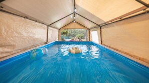 An indoor swimming pool with clear blue water, surrounded by beige walls and a peaked roof structure. - Daebudo Freesia Private Pool Villa (Ansan)