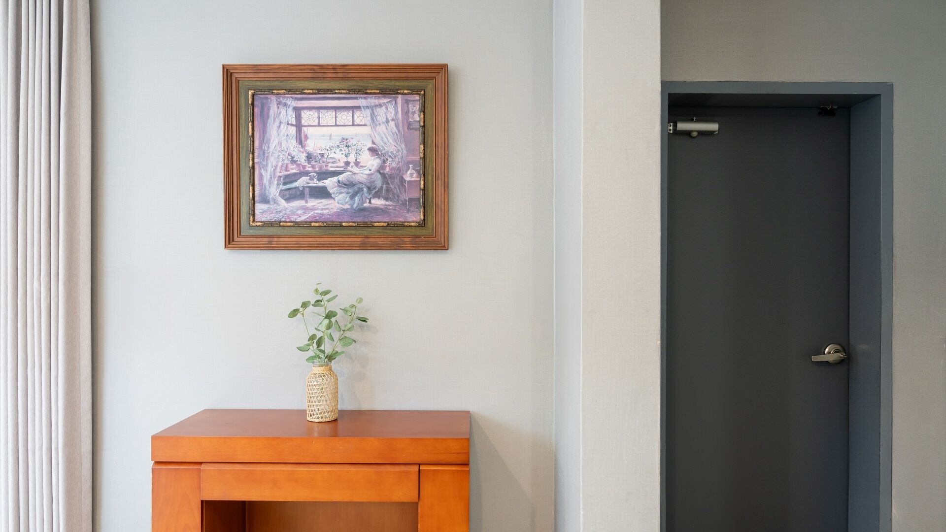 Una habitació amb un armari de fusta, un quadre amb marc i una porta fosca.