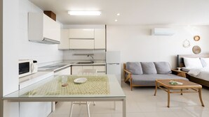A modern kitchen with white cabinets, a microwave, and a dining table with a glass top. - The Seaside 2, Taean (Taean)