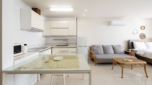 Una cocina moderna con armarios blancos, un microondas y una mesa de comedor con superficie de vidrio.