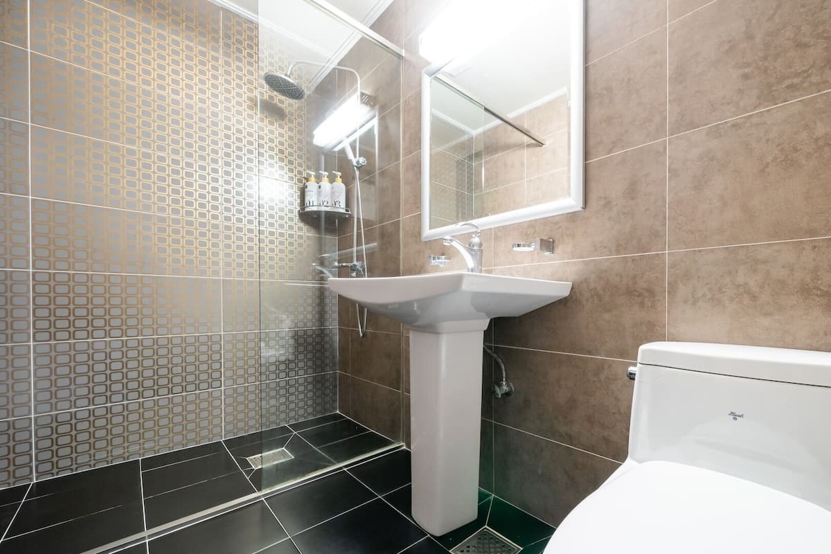 A modern bathroom with a shower, sink, and toilet.
