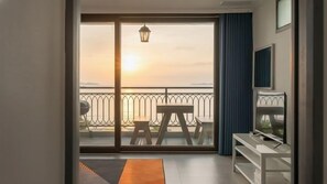 A room with a sliding glass door leading to a balcony with a view of the sunset. - The Seaside 2, Taean (Taean)