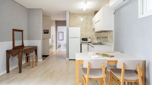 Una cocina moderna con comedor, muebles de madera y un refrigerador blanco.
