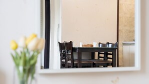 Un comedor con una mesa, sillas y un jarrón de flores.
