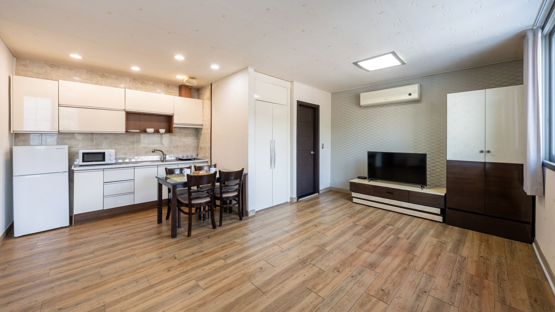 A modern kitchen with white cabinets, a microwave, and a dining area with a table and chairs.