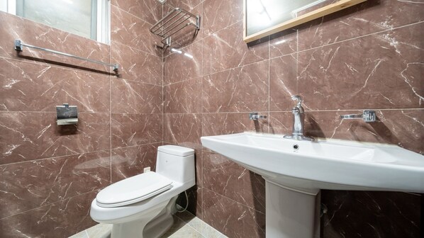Une salle de bain équipée de toilettes, d’un lavabo et d’un porte-serviettes.