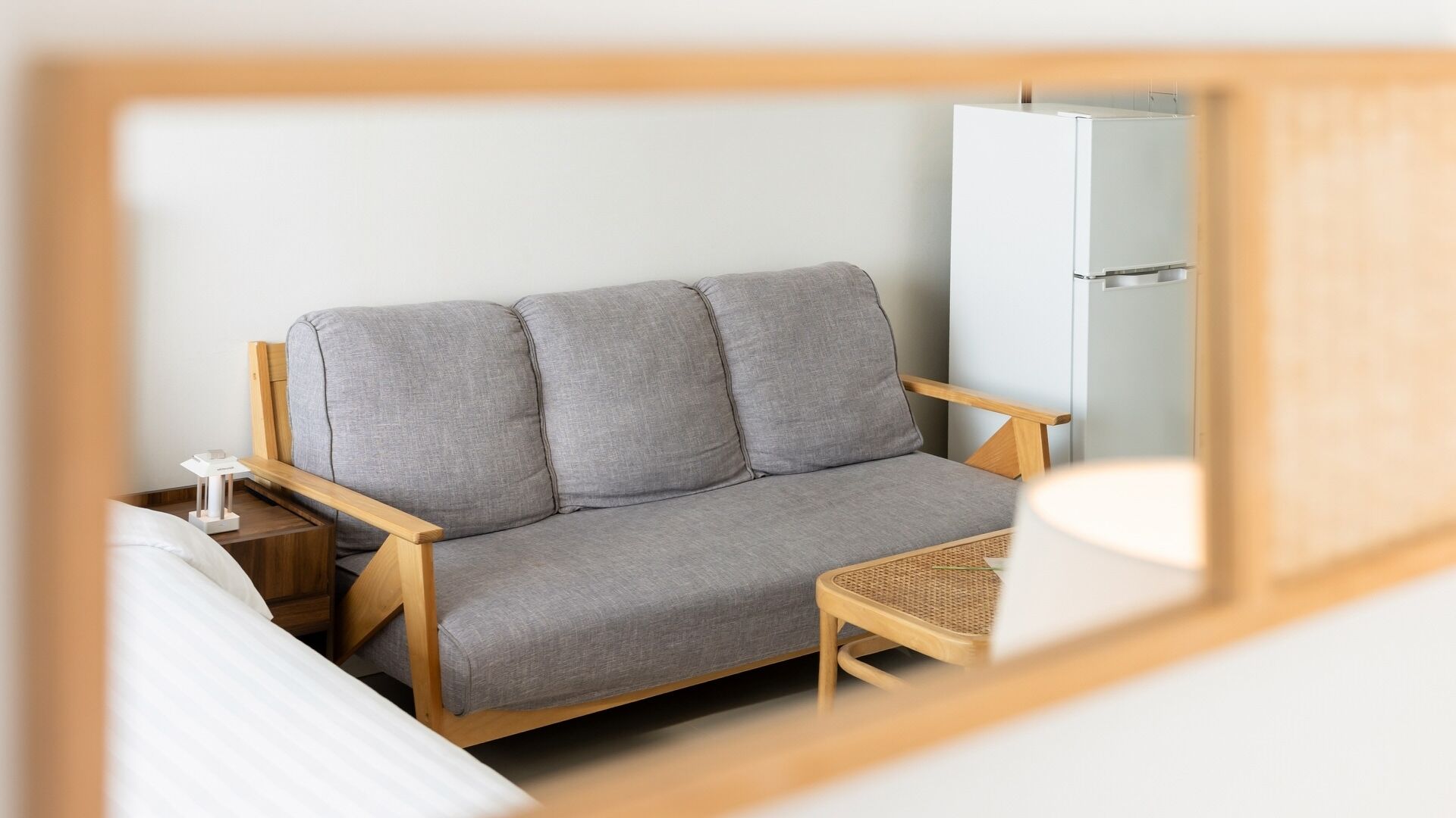 A room with a grey sofa, wooden armchairs, a small table, and a wardrobe.