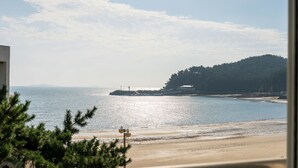 A beach with a sandy shore, a small island with structures, and a forested hill in the background. - The Seaside 2, Taean (Taean)
