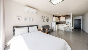 Una habitación de hotel moderna con cama, escritorio, silla y kitchenette.