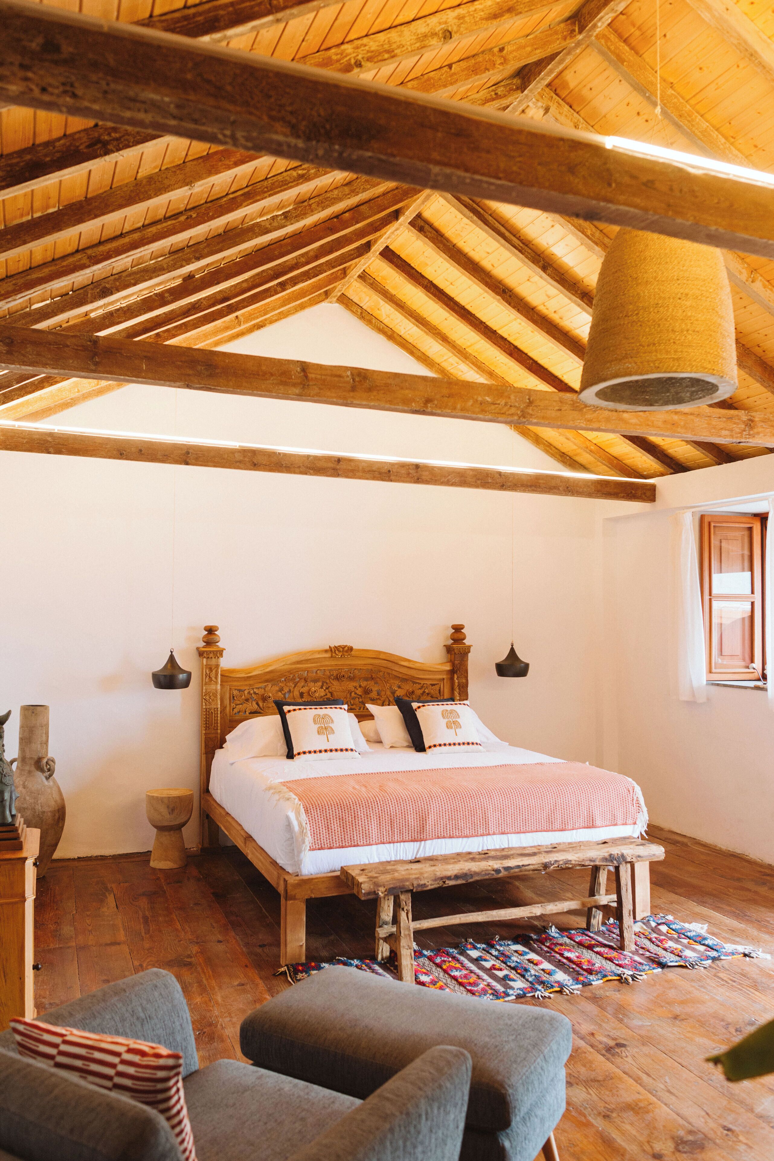 A rustic bedroom with a wooden bed, a hanging light fixture, and a wooden floor.