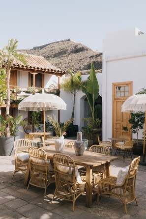 An outdoor patio with wicker furniture, white umbrellas, and potted plants. - Dreamsea Gran Canaria Boutique (Moya)