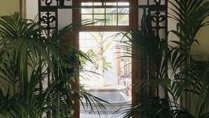 An ornate wrought iron gate with the initials "JHM" above it, leading to a tiled corridor with potted plants on either side. - Dreamsea Gran Canaria Boutique (Moya)