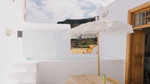 A white-walled room with a wooden table and chairs, a green vase, and a white umbrella. - Dreamsea Gran Canaria Boutique (Moya)